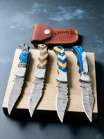 Four Damascus pocket knives with colorful handles on a wooden block, with a leather sheaths one with pocket clip labeled 'ZB Knives' in the background.